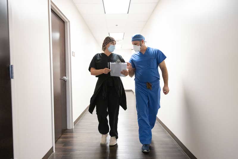 Two physicians talking while walking down hallway